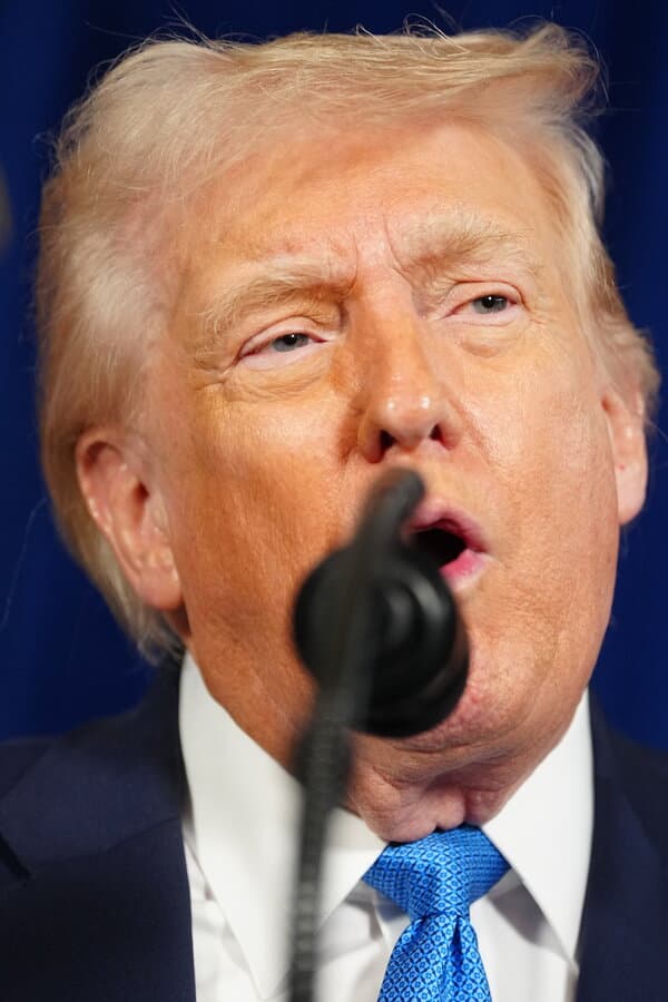 Donald Trump speaking at a podium with American flags in the background