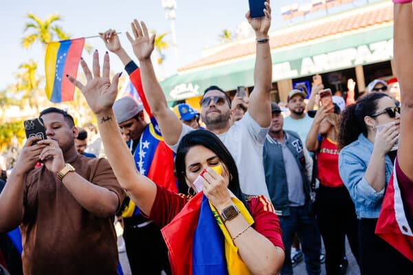 Venezuelan immigrants in Florida gathering at a community event, discussing the possibility of returning to their homeland