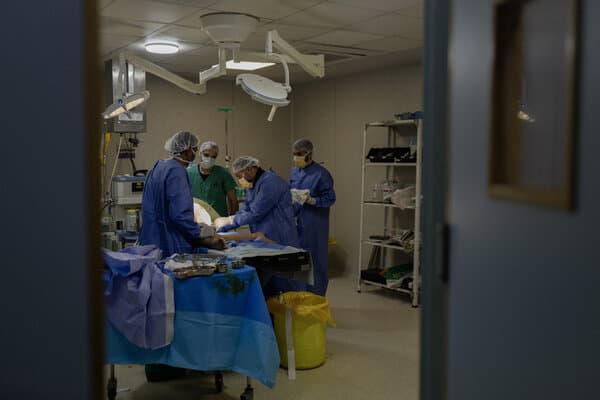 A doctor in medical scrubs treats a patient in a makeshift Gaza clinic amid ongoing conflict
