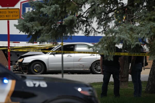 A crime scene barrier and emergency vehicles in a Minneapolis neighborhood following a shooting incident involving ICE agents.