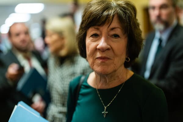 Donald Trump speaking at a podium while Senator Susan Collins looks on