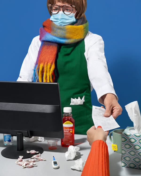A worried employee looking at a computer screen while holding a thermometer, representing workplace sick day anxiety.